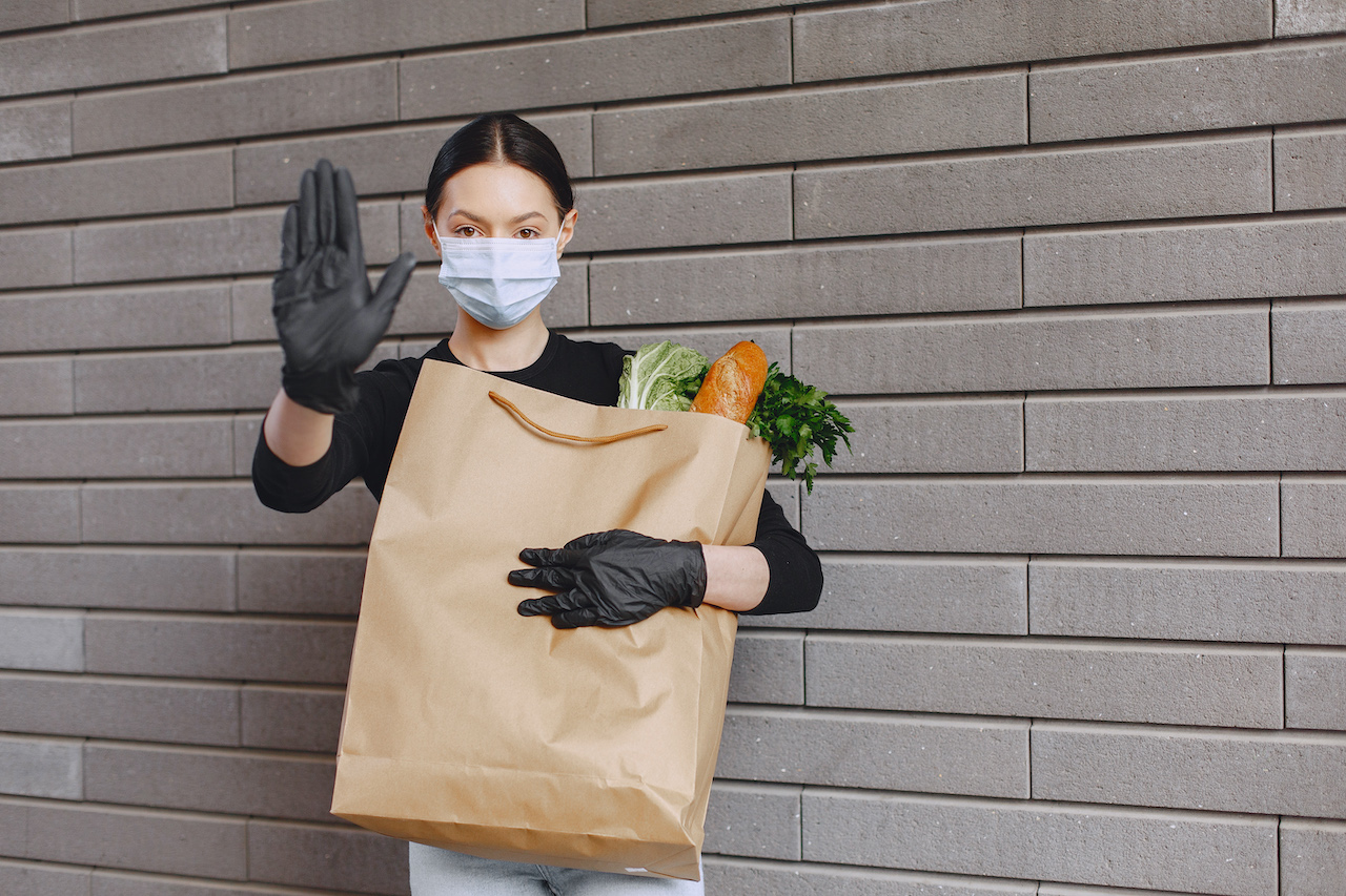 Girl in protective mask holds package with products